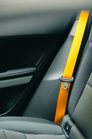 A vehicle interior with a bright yellow seatbelt running diagonally across a grey seat and door trim.